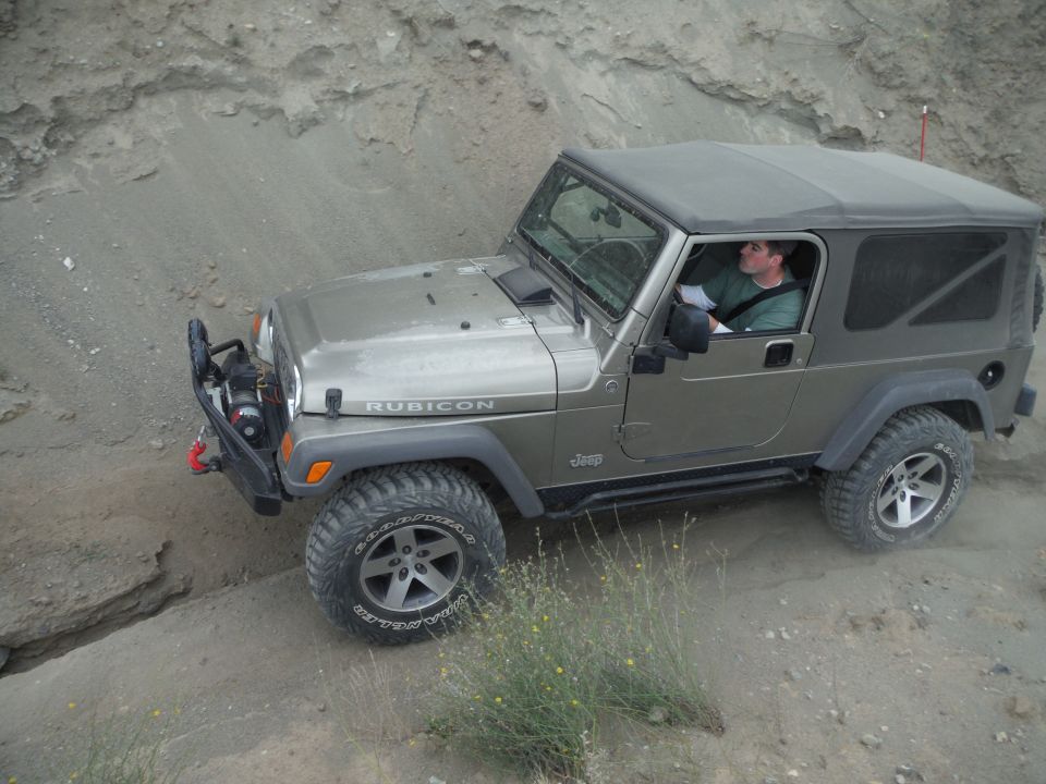 Jeep Wrangler Rubicon driving on a dirt trail with a driver inside