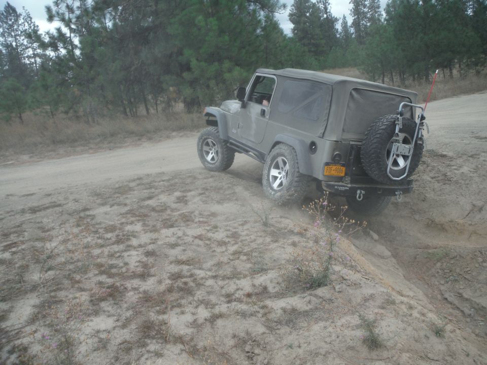 Gray 2005 Jeep Wrangler on dirt path, rear view