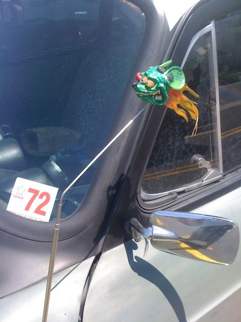 1968 Ford Mustang - A car's side mirror and windshield frame are visible, adorned with a quirky green creature ornament and a sticker showing the number 72.