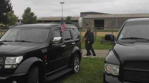 1991 Ford LTD Crown Victoria - Two men walk past a black Dodge Nitro SUV parked on grass near some farm buildings.