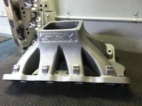 1972 Ford Ranchero - Close-up of automotive engine parts, an intake manifold and cylinder head, on a textured surface.