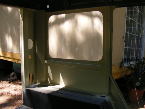 Interior of a light green vehicle, showing a large window opening and structural elements