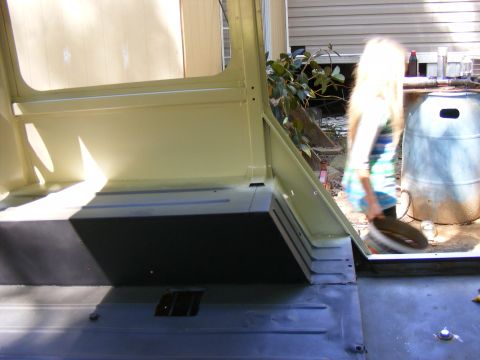 Interior view of a vehicle with light yellow walls and dark floor, a person walks by