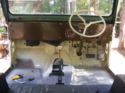 Interior of a Jeep CJ, showing dashboard, steering wheel, pedals, and floor