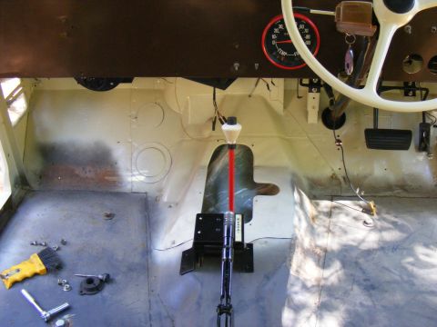 Interior view of a vehicle showing a floor shifter, dashboard gauges, and pedals