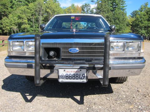 1991 Ford LTD Crown Victoria - Head-on view of a black Ford sedan's grille, quad headlights and push bar, with a California plate reading 888849 mounted at the front.