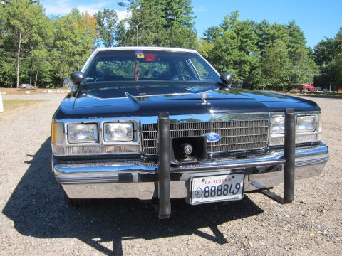1991 Ford LTD Crown Victoria - Front view of a black Ford with a chrome grille, hood ornament and push bar, displaying a California license plate reading 888849.