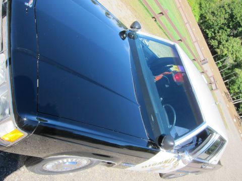 1991 Ford LTD Crown Victoria - Tilted view over the long black hood and white roof of a patrol car, showing the windshield, side mirror and orange interior detail.