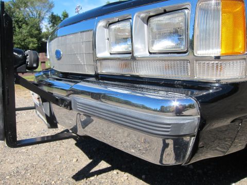 1991 Ford LTD Crown Victoria - Low front-end view of a black vehicle showing dual rectangular headlights, chrome bumper, Ford grille badge and a black push-bar bracket.