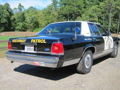 1991 Ford LTD Crown Victoria - Rear three-quarter view of a black-and-white police Crown Victoria with roof emergency lights and California plate '888849' on gravel.