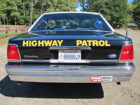 1991 Ford LTD Crown Victoria - Direct rear view of a black-and-white Ford Crown Victoria police car with yellow 'Highway Patrol' trunk lettering and California plate '888…