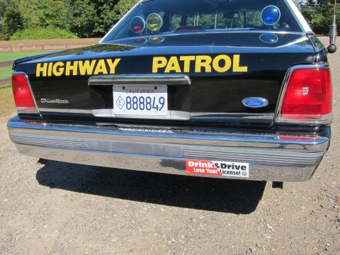1991 Ford LTD Crown Victoria - Rear of a black-and-white police Crown Victoria showing yellow 'Highway Patrol' trunk text and a 'Drink & Drive Lose Your License' bumper s…