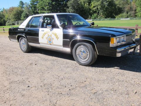 1991 Ford LTD Crown Victoria - Front-quarter view of a black-and-white California Highway Patrol full-size sedan, gold star emblem on the white front door.