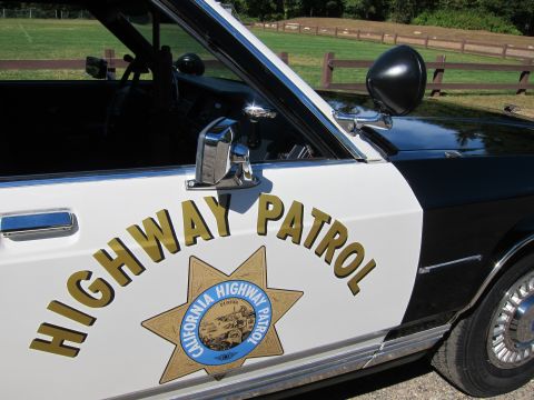 1991 Ford LTD Crown Victoria - Close-up of a patrol car door reading HIGHWAY PATROL with the California Highway Patrol star, A-pillar spotlight and black mirror above.