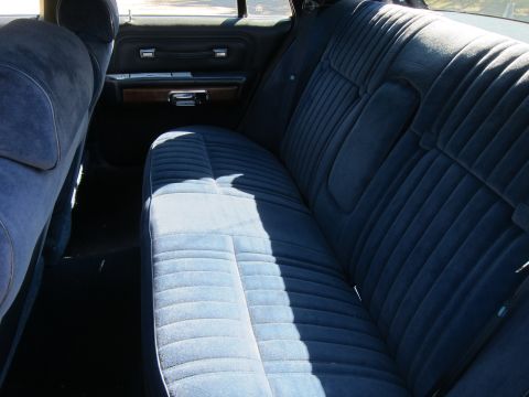 1991 Ford LTD Crown Victoria - Interior view of a blue cloth rear bench seat with woodgrain door trim inside a full-size sedan.