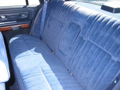 1991 Ford LTD Crown Victoria - Blue cloth rear bench seat seen across the cabin, with woodgrain door panel and rear parcel shelf above.