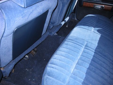 1991 Ford LTD Crown Victoria - Interior shot showing the back of a blue cloth front bench and the rear bench seat with dark blue carpet.