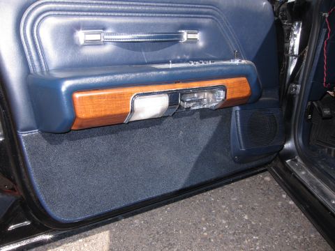 1991 Ford LTD Crown Victoria - Open blue vinyl front door panel with woodgrain accent, chrome handle and a round speaker grille at the bottom.