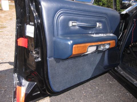 1991 Ford LTD Crown Victoria - Open blue vinyl door panel with woodgrain accent and chrome handle; a paper label is visible on the door jamb.