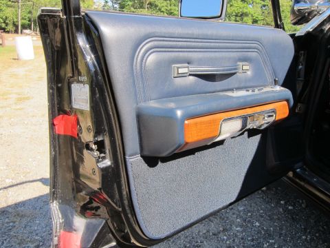 1991 Ford LTD Crown Victoria - Open blue vinyl door panel showing amber side reflector, woodgrain accent, chrome handle and a label on the jamb.