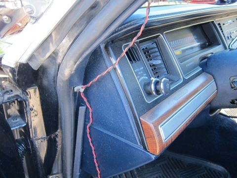 1991 Ford LTD Crown Victoria - Passenger side of an older car's dashboard showing wood-grain trim, vents, and a red wire routed down the kick panel.