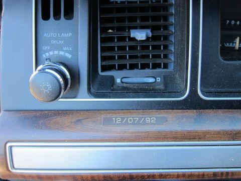 1991 Ford LTD Crown Victoria - Close-up of a dashboard headlight knob with Auto Lamp Delay markings and a vent, with a 12/07/92 build-date stamp on the wood-grain trim.