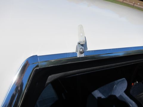 1991 Ford LTD Crown Victoria - chrome latch hook on the trunk lid of a black car, with chrome window trim and a glimpse of the interior below.