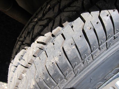 1991 Ford LTD Crown Victoria - Close-up of the worn tread blocks of an all-season tire mounted on a vehicle wheel.