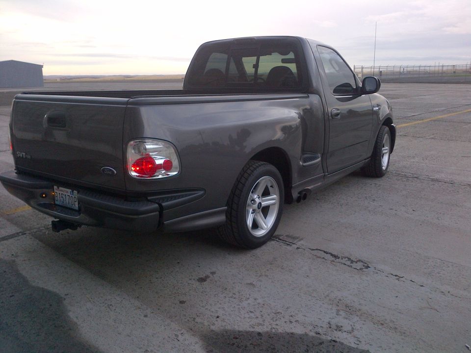 Dark gray 2003 Ford F-150 SVT Lightning pickup truck, rear 3/4 view, parked on asphalt