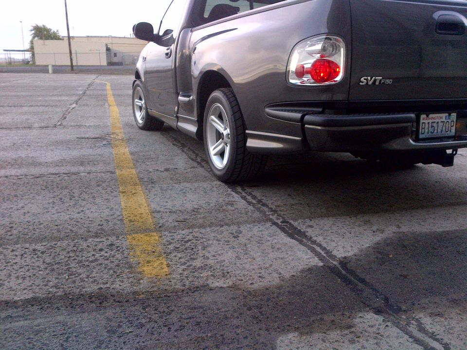 Rear 3/4 view of a dark gray 2003 Ford F-150 SVT Lightning pickup truck parked on asphalt