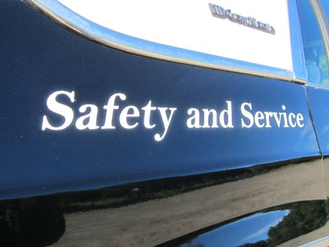 1991 Ford LTD Crown Victoria - White Safety and Service lettering on the black rear door of a car, with a chrome script emblem above the window line.