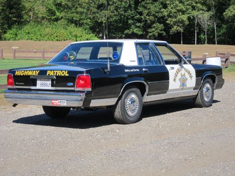 1991 Ford LTD Crown Victoria - Rear three-quarter view of a black-and-white Highway Patrol Ford sedan with a California plate reading 888849 and roof-mounted emergency li…