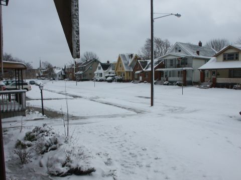 2001 Ford Taurus - A quiet residential street covered in snow, with several houses and parked vehicles visible.