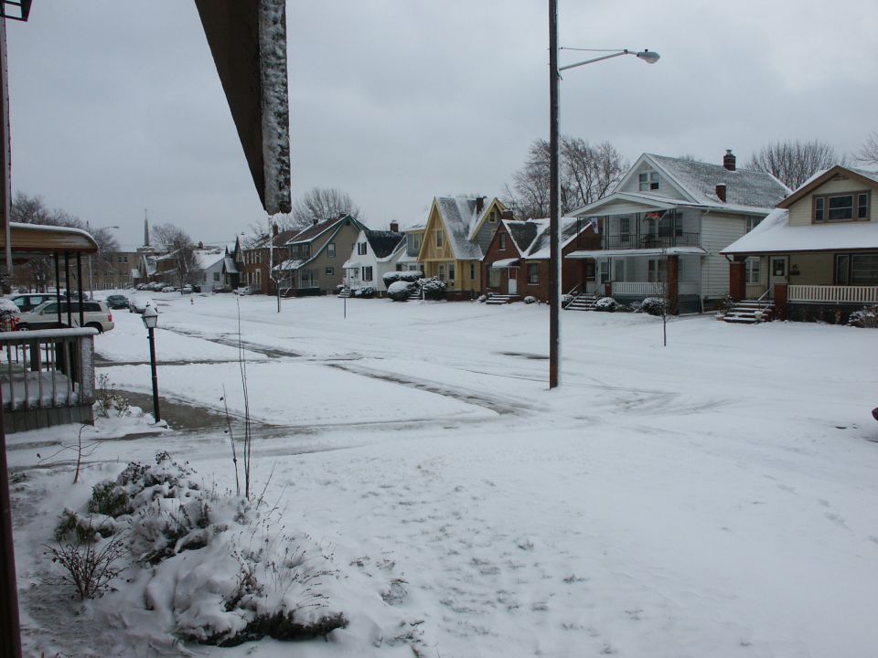 Snowy street scene with houses and parked cars