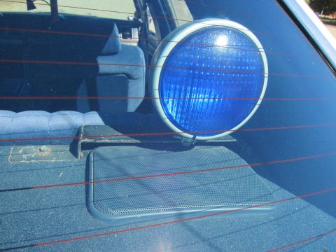 1991 Ford LTD Crown Victoria - single round auxiliary lamp with a blue lens mounted on the rear parcel shelf inside a car behind the rear window.