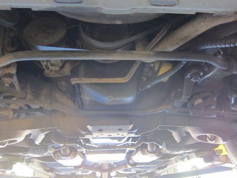 1991 Ford LTD Crown Victoria - Undercarriage shot looking up at a vehicle's front sway bar, crossmember and exhaust components on a lift.