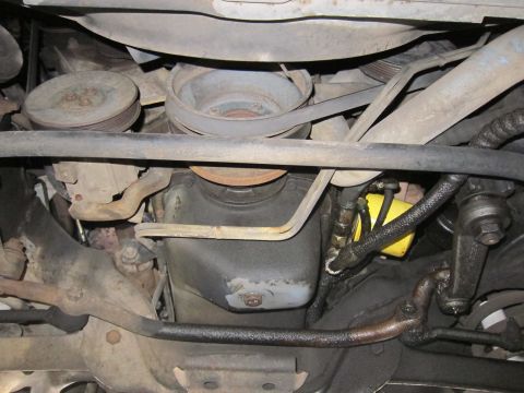 1991 Ford LTD Crown Victoria - Undercarriage view showing accessory pulleys, the front sway bar and a yellow-tagged wire or hose on a vehicle.