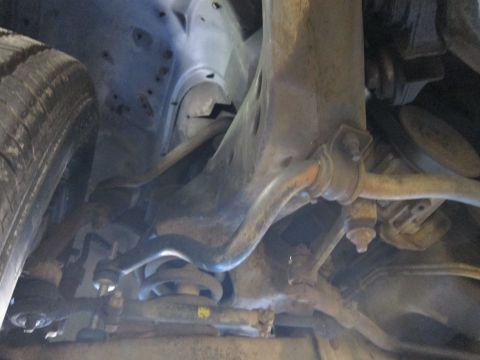 1991 Ford LTD Crown Victoria - Low-angle undercarriage shot of a front wheel, control arm, sway bar and steering components on a lift.