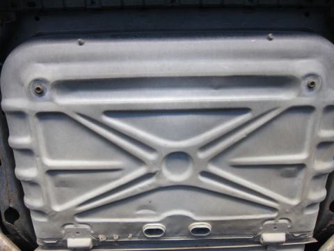 1991 Ford LTD Crown Victoria - Undercarriage view of a large stamped sheet-metal panel with an X-shaped reinforcement, likely a fuel tank skid or tank.