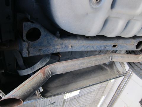 1991 Ford LTD Crown Victoria - Undercarriage view showing a crossmember, oil pan and a single exhaust pipe ending in an angled tailpipe.