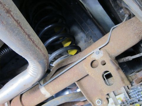1991 Ford LTD Crown Victoria - Undercarriage view of a rear coil spring with yellow paint mark, control arm and a rusty mounting bracket.