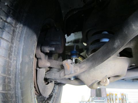 1991 Ford LTD Crown Victoria - Undercarriage view of a front disc brake caliper, coil spring and lower control arm with a blue-marked ball joint.