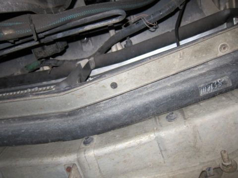 1991 Ford LTD Crown Victoria - Undercarriage close-up showing hoses, wiring, and a stamped sheet-metal panel with a handwritten number.