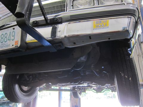 1991 Ford LTD Crown Victoria - Vehicle raised on a lift, viewed from below the front, showing grille, bumper, and a New Hampshire license plate ending in 8849.