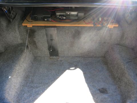 1991 Ford LTD Crown Victoria - Carpeted car trunk interior with electronic equipment and wiring mounted on a wooden board across the top.