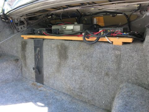 1991 Ford LTD Crown Victoria - Carpeted trunk interior with electronic equipment, a coiled hose, and wiring mounted on a wooden board.