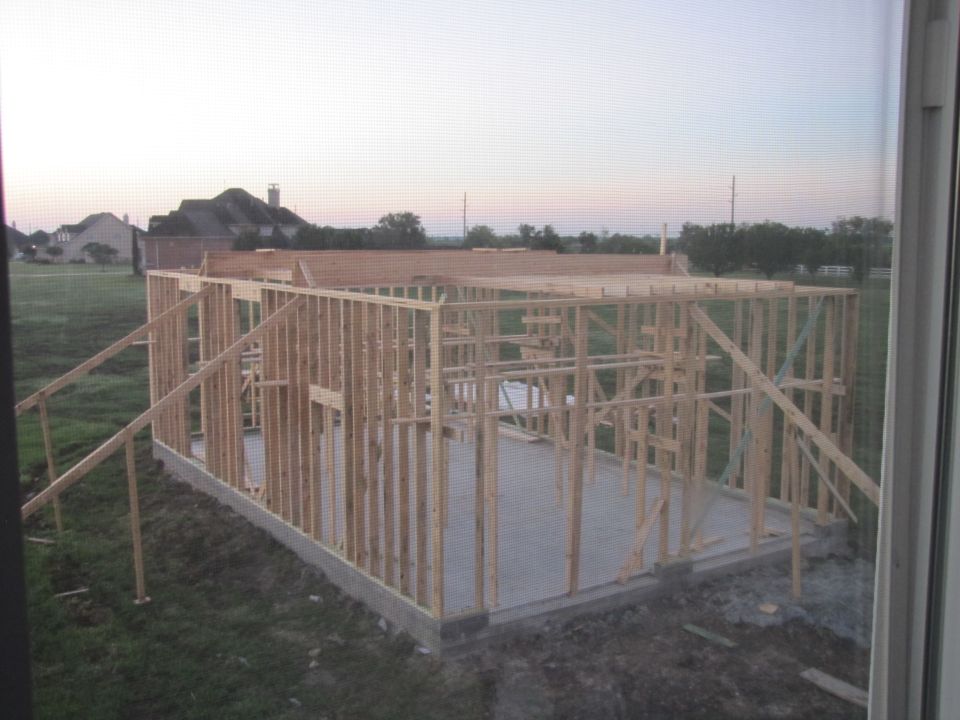 House framing in progress with concrete foundation and wooden studs visible