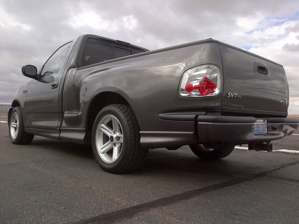 Gray Ford F-150 SVT Lightning pickup truck, rear 3/4 view. Has custom wheels and SVT badging