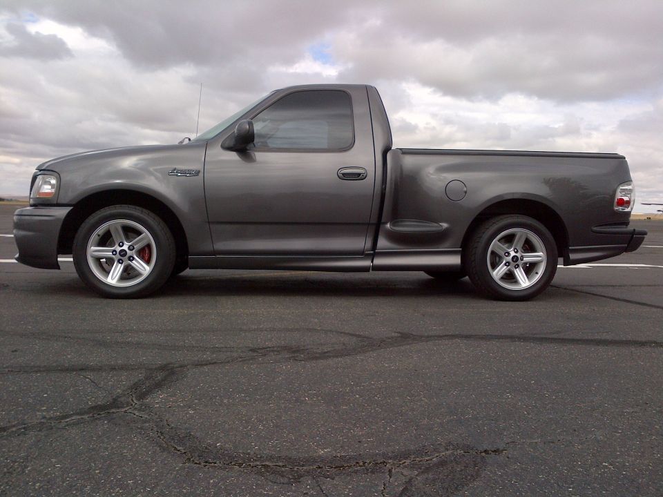 Gray 2003 Ford F-150 Lightning pickup truck, side view, showing custom wheels and lowered suspension