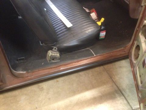 1972 Ford Ranchero - The interior floor and seat of a vehicle show signs of wear and some cleaning supplies.